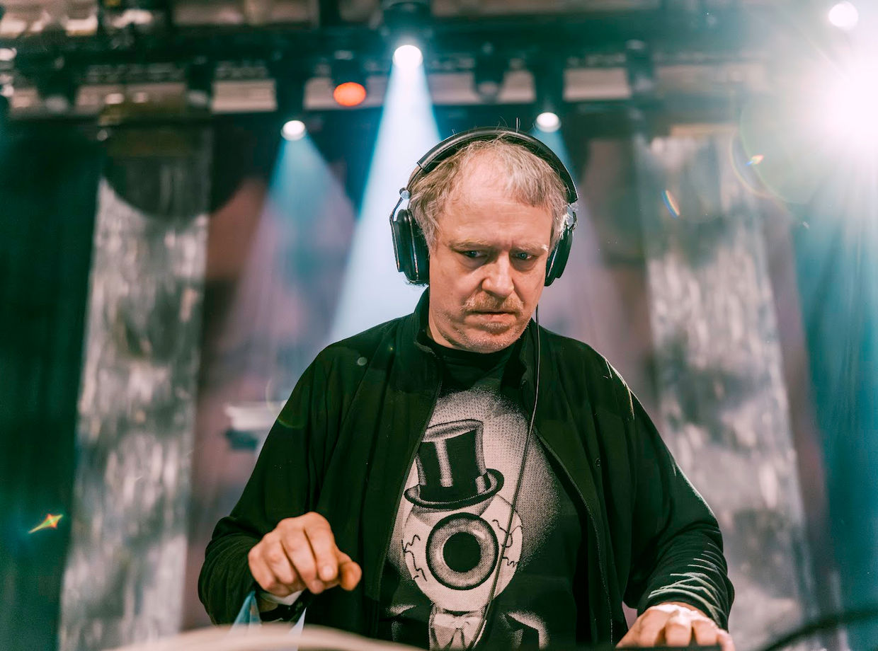 The DJ in headphones, deep in the mix