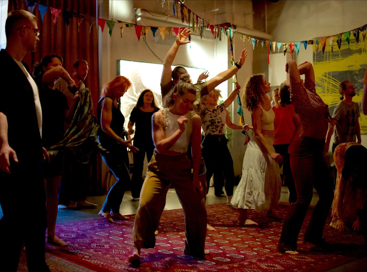 Dancers with their arms up in front of the bright screen