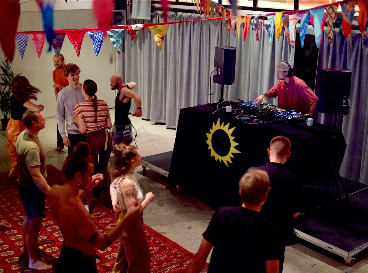 Dancers in front of the DJ booth with the Morning Beat sun